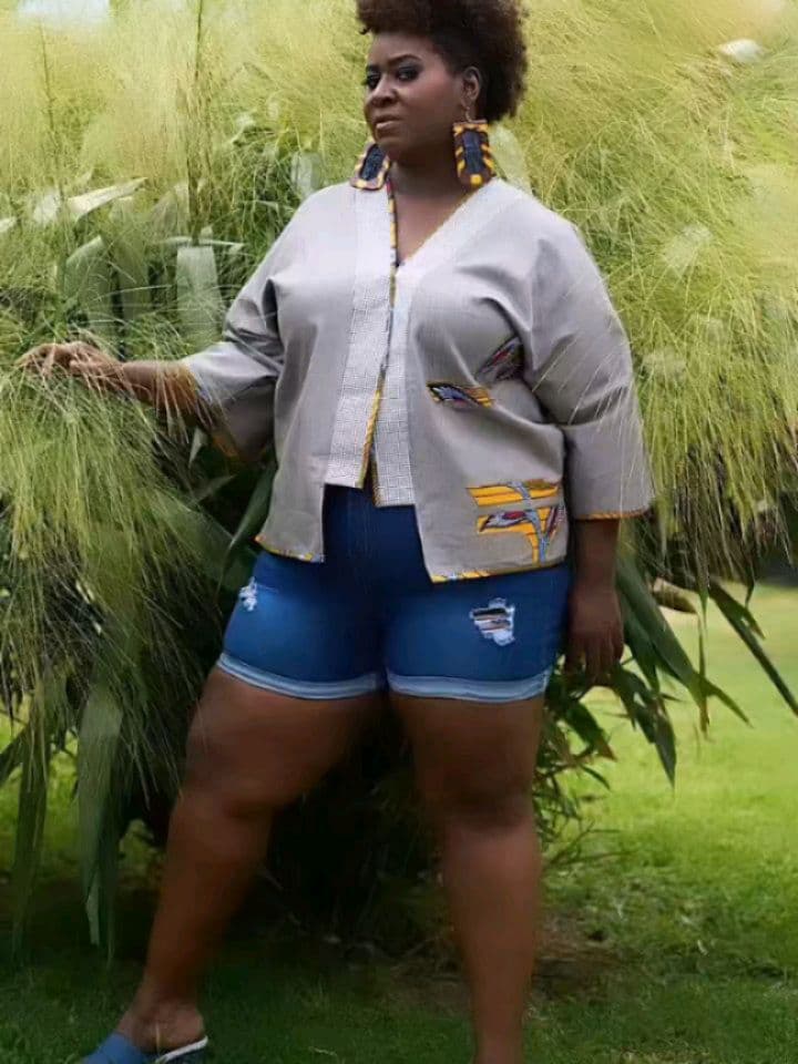 Veste kimono grise à empiècements wax portée avec un short en jean, en extérieur